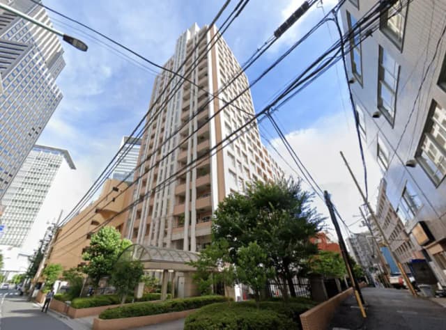 - 高層ビルと周囲の街並み、青空の下、電線が交差する都市風景