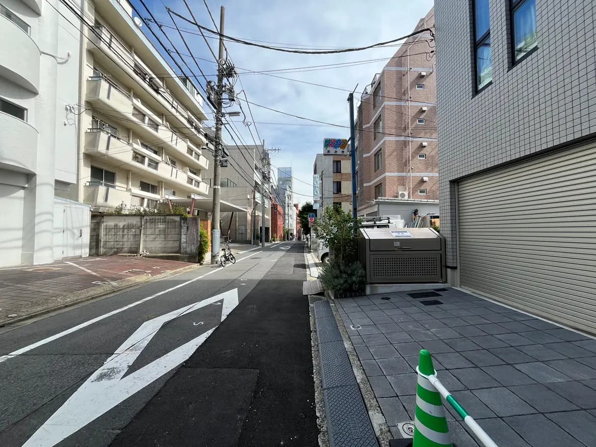 - 住宅街の街並み、両側に高層ビルと低層住宅が並び、車道と歩道が整備された静かな通りの風景
