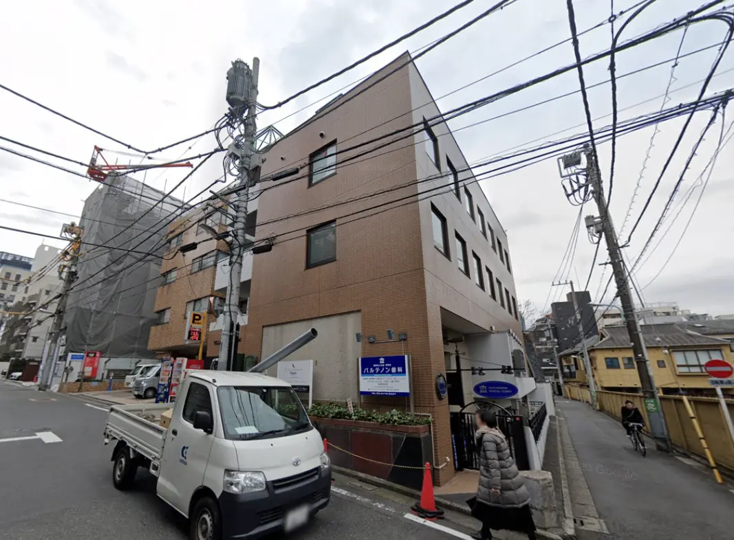 - 住宅街にある現代的な外観の中層マンション、周囲に電柱と電線が見える風景