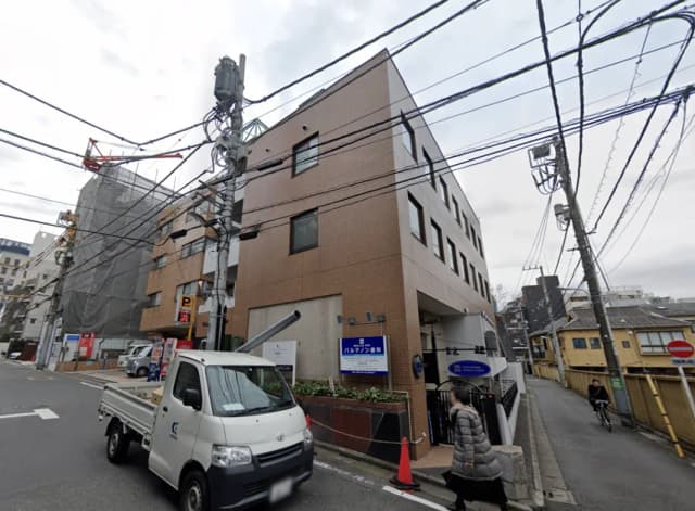 - 住宅街にある現代的な外観の中層マンション、周囲に電柱と電線が見える風景
