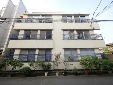 - バルコニー付きの4階建てアパート、外観に青い手すりと植物が配置された街並みの風景