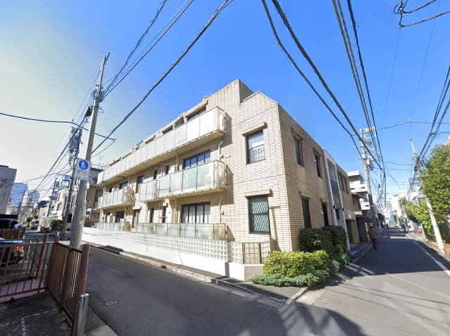 - 鉄筋コンクリート造のアパートメント、バルコニー付きの2階建て、周囲に草木や電柱が並ぶ街並みの風景