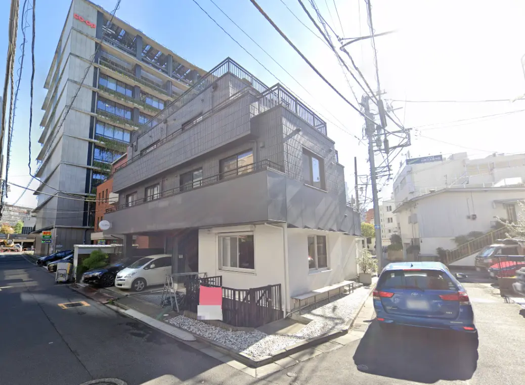 - モダンなデザインの建物と周囲の道路、駐車スペースに停まる車、晴れた日の明るい風景