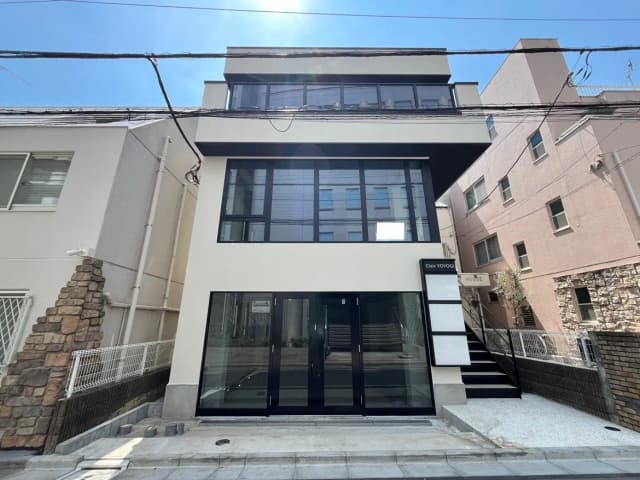 - モダンな外観の3階建て住宅、黒いフレームの大きな窓と白い壁、整然としたエントランスのデザイン