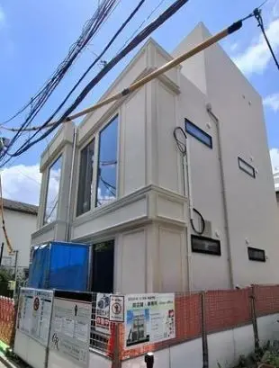 - モダンなデザインの2階建て住宅、広い窓と白い外壁、工事中の看板と作業用ネットが見える外観