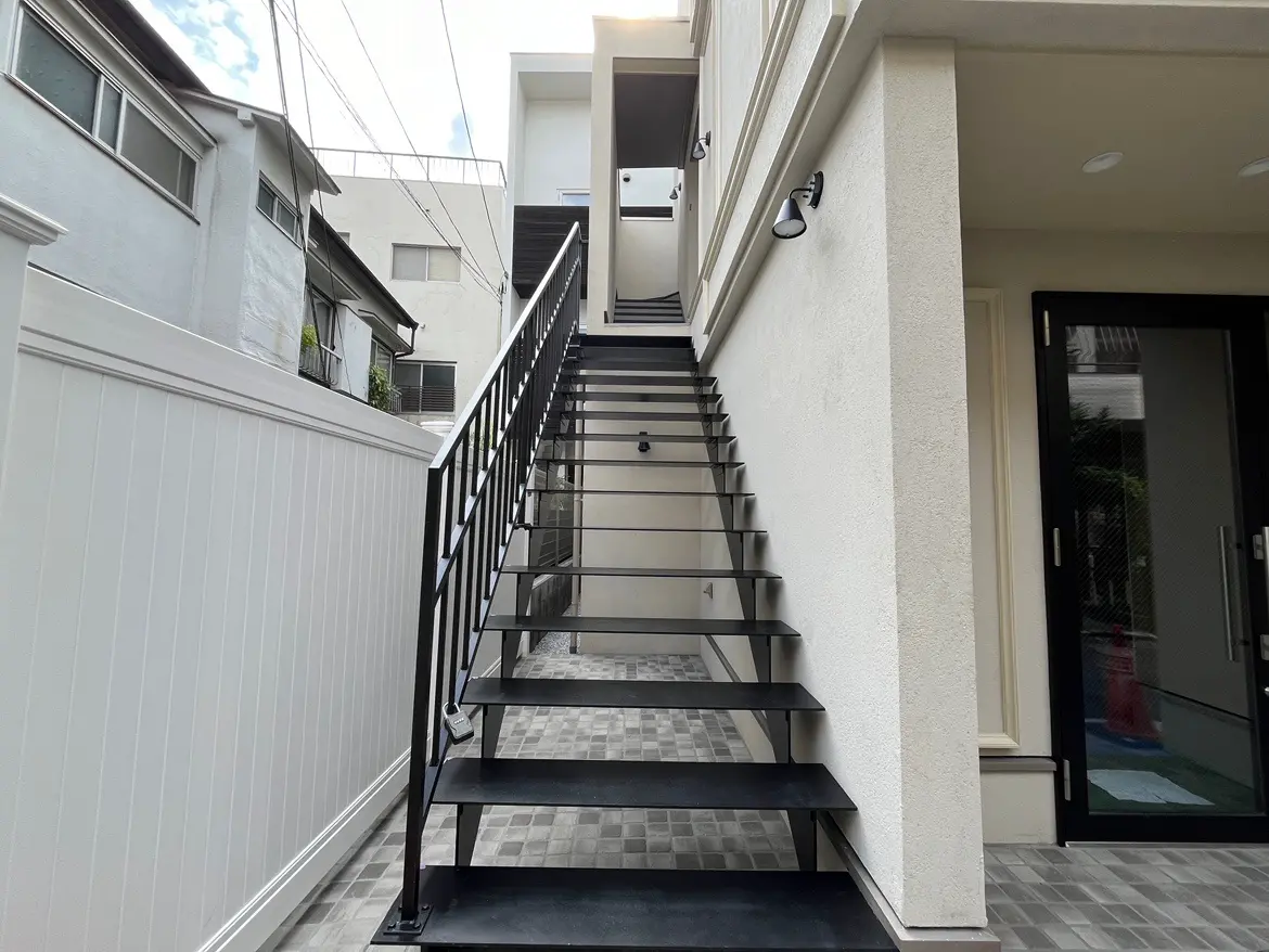 - モダンなデザインの外階段、黒いステップと白い壁、周囲の住宅が映り込む風景