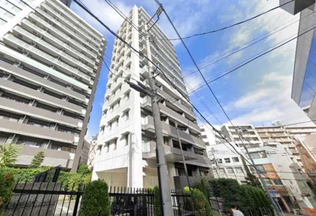 - 現代的なデザインの高層マンション、隣接するビルと電柱が見える街中の風景