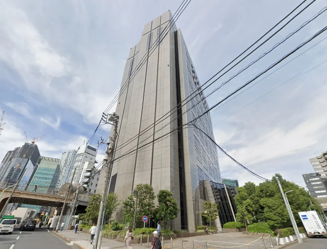 - 高層ビルの外観、周囲の街並みと道路、電柱や電線が見える都市景観