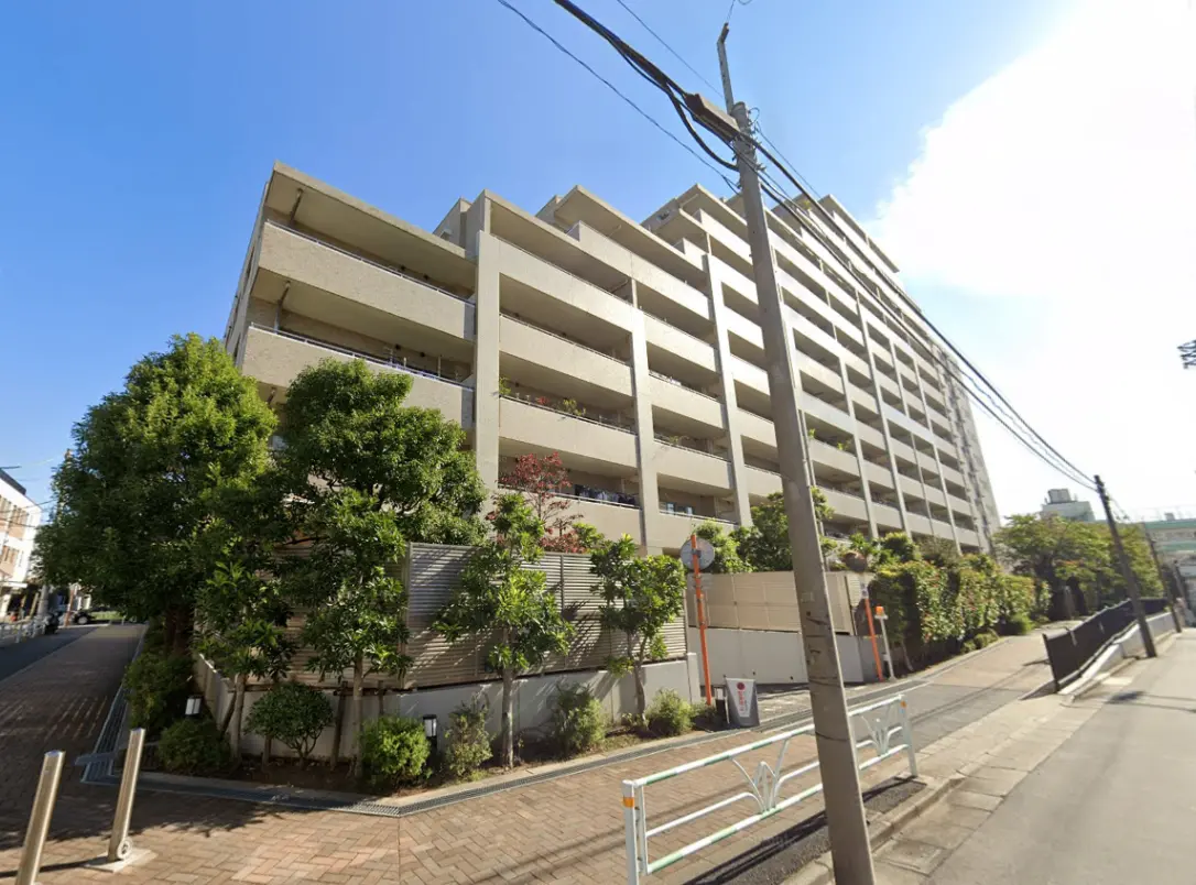 - 緑豊かな街並みに佇む現代的なマンションの外観、バルコニーや植栽が調和したデザイン