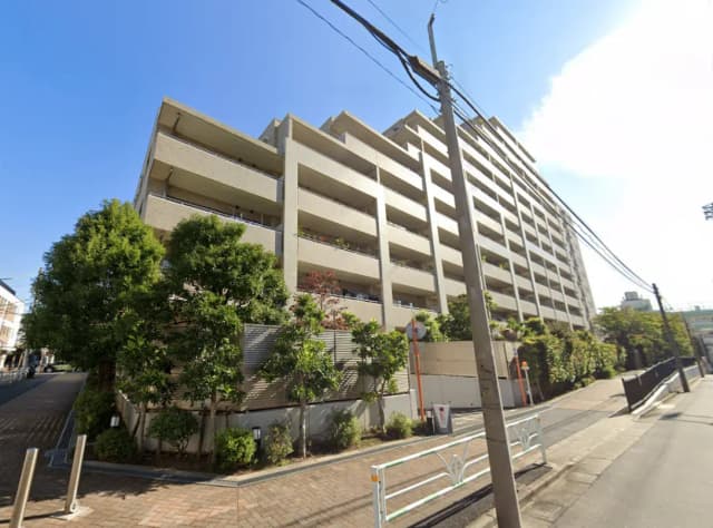 - 緑豊かな街並みに佇む現代的なマンションの外観、バルコニーや植栽が調和したデザイン