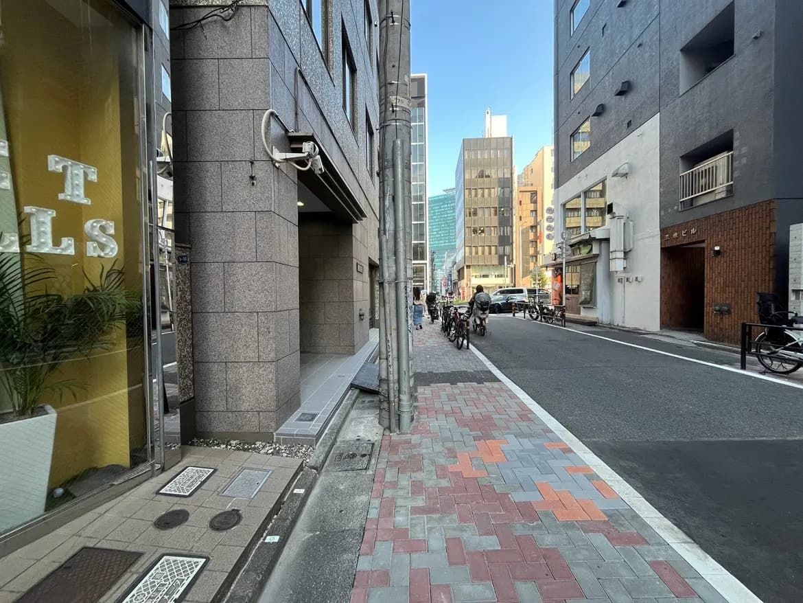 - 都会の風景、歩道に並ぶ自転車と建物が立ち並ぶストリートシーン、青空が広がる日中の街並み