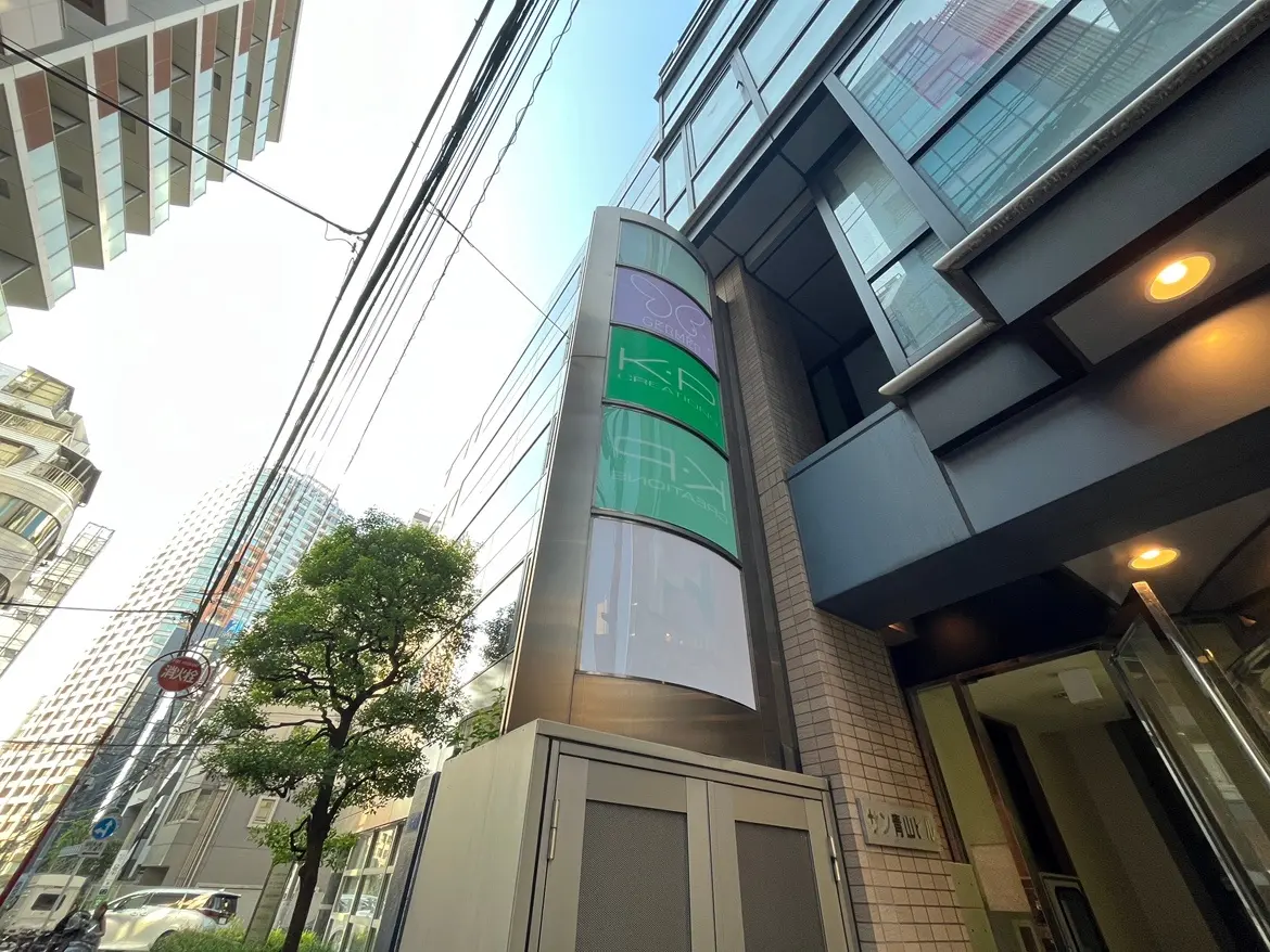 - 高層ビルの外観、モダンなデザインのエントランス、投影された広告がある街並みの風景