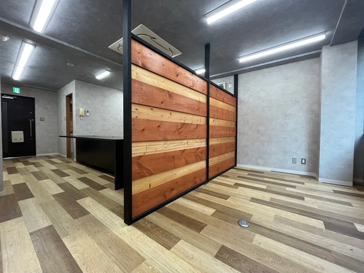 - モダンなオフィススペース、木目調のパーティションと光沢のあるフローリング、シンプルなデザインのインテリア
