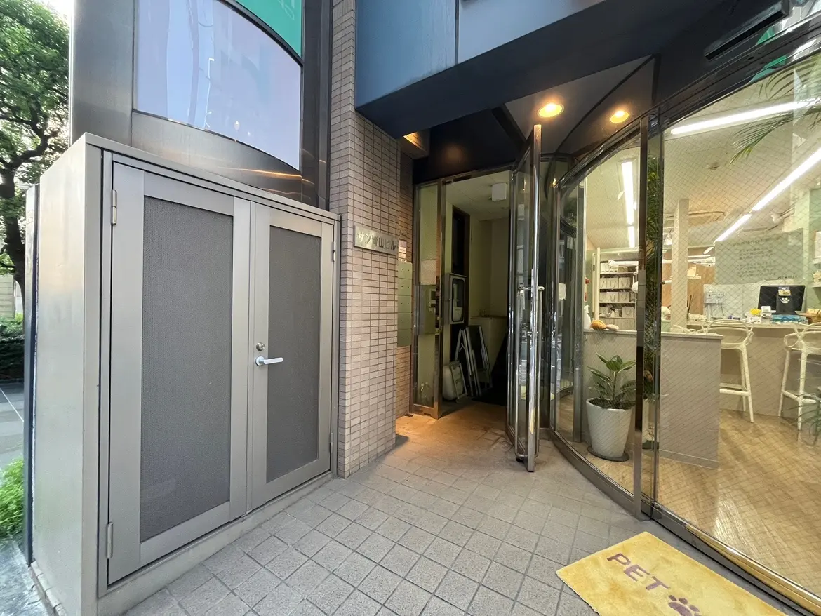 - 現代的なデザインの店舗入口、透明な自動ドアと丸みを帯びた屋根、ペット用のウェルカムマットが敷かれたエントランスの外観