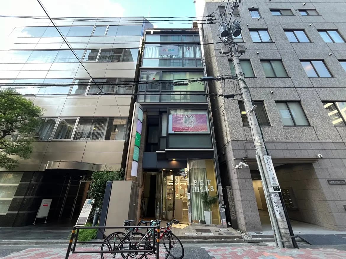 - 近未来的なデザインの商業ビル、ガラス張りの外壁、ビジネス街に立地するペットショップのエントランスが見える風景