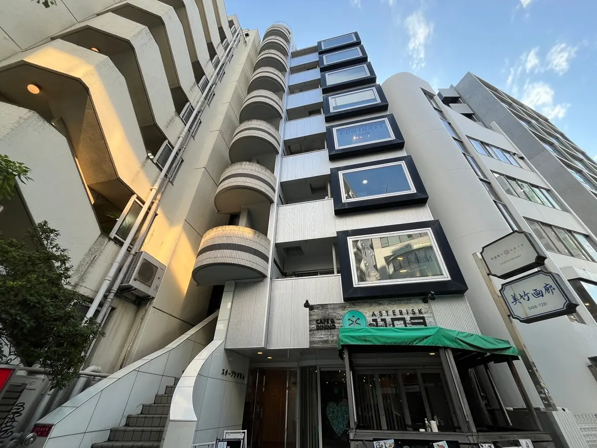 - モダンなデザインのビル外観、バルコニーが特徴的で、明るい照明が施されたカフェの入口と隣接する建物の様子