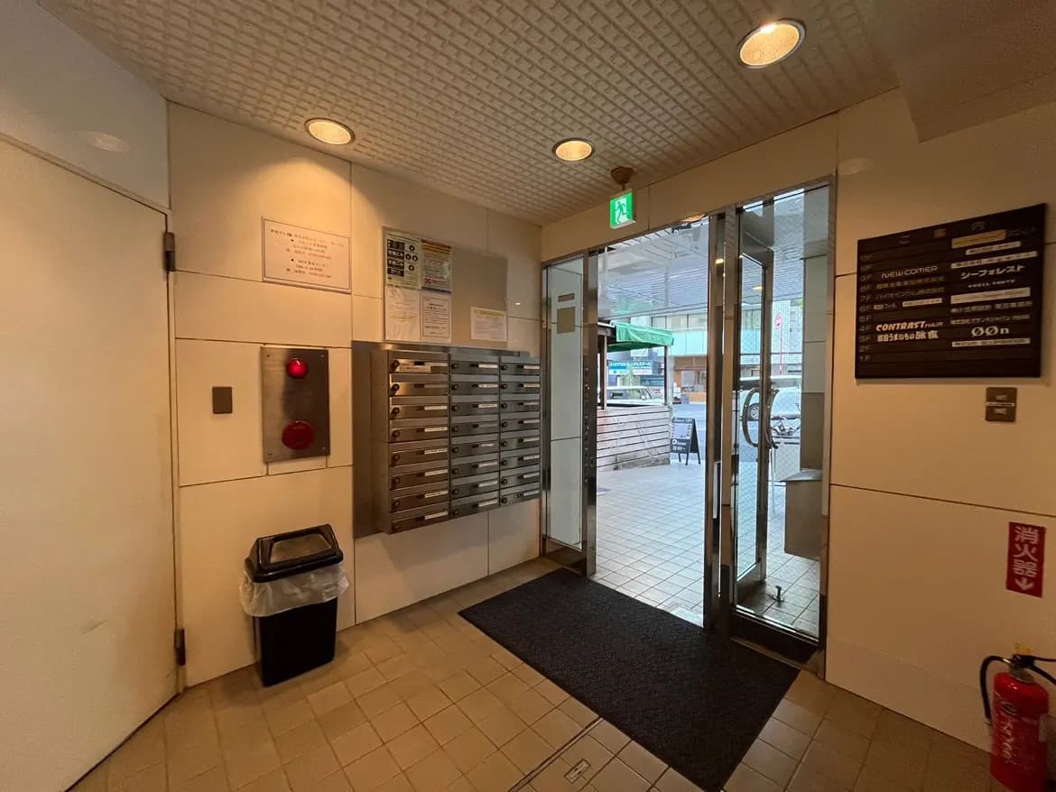 - エントランスのインテリア、郵便受け、消火器表示、明るい照明と開放的な入口の様子