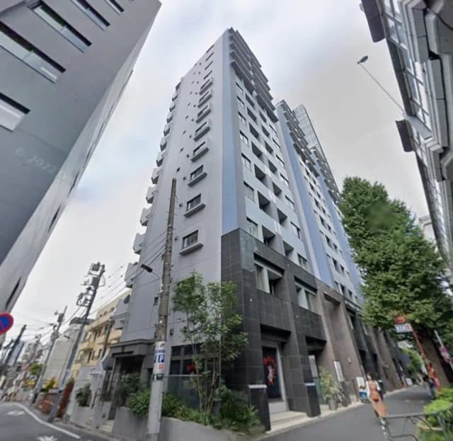 - モダンな外観の高層マンション、黒とグレーのタイル張り、周囲に緑と街灯のある通りの風景