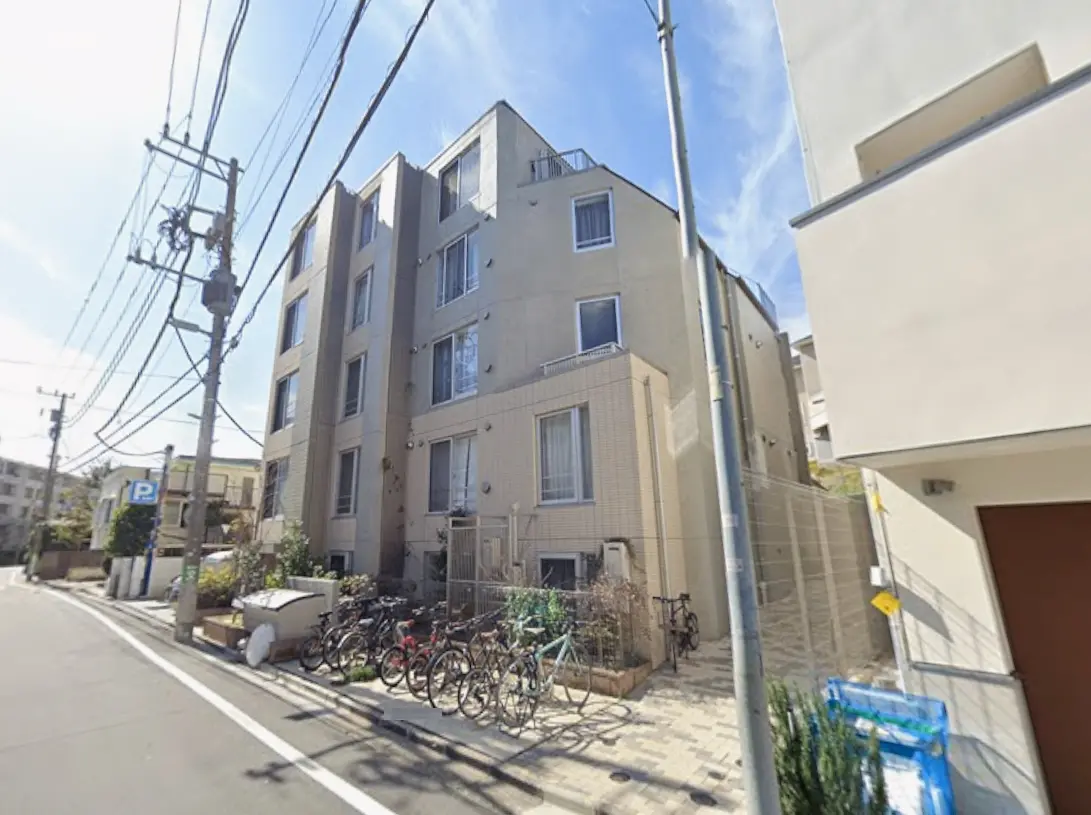 - 自転車が並ぶ住宅街のアパート外観、電柱と空が見える街並みの景観