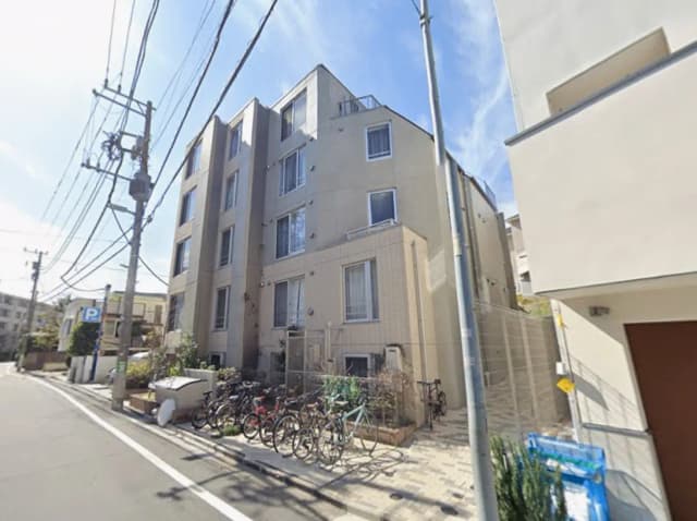- 自転車が並ぶ住宅街のアパート外観、電柱と空が見える街並みの景観