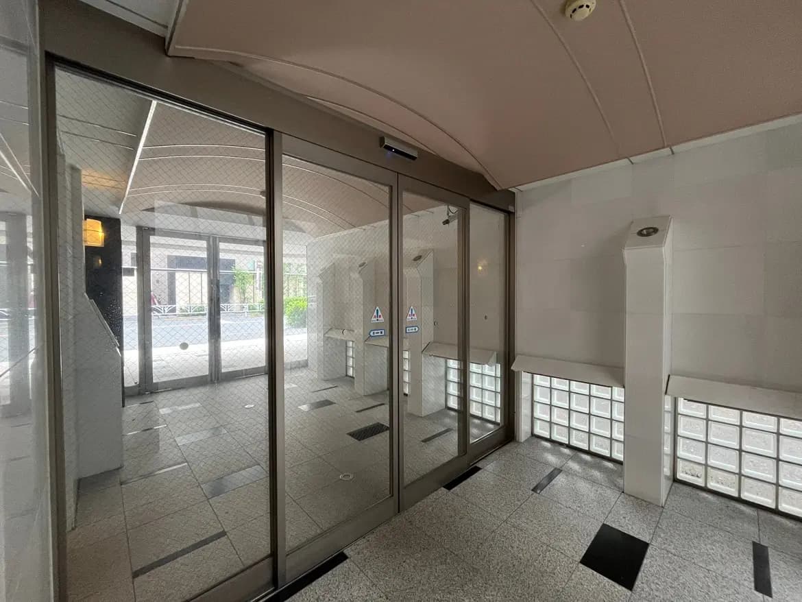 - 透明なガラスドアのあるエントランスホール、モザイクタイルの床と自然光が差し込む明るい空間