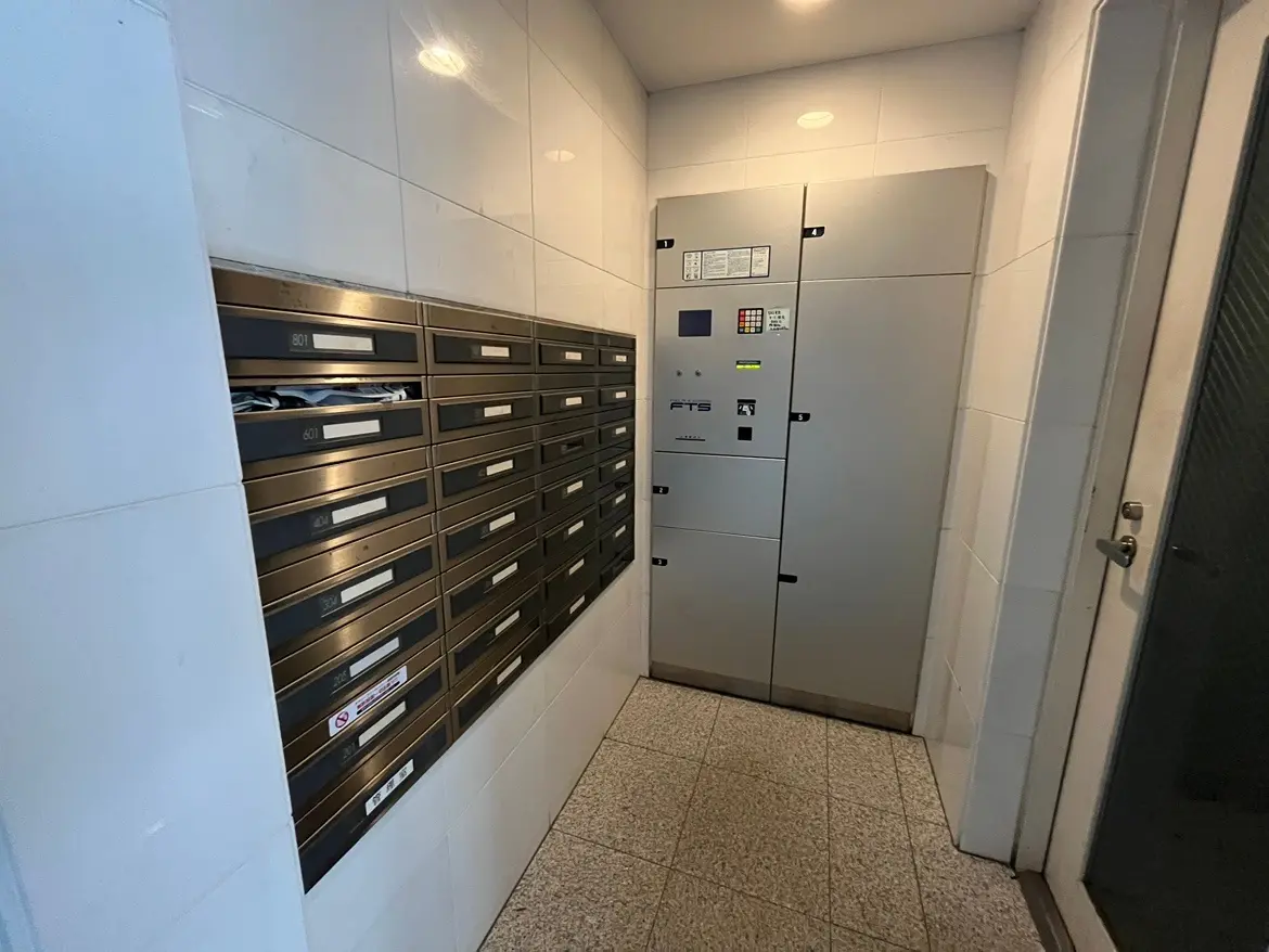 - モダンな宅配ボックスと郵便受けが設置されたエントランスの内部、清潔感のあるタイル張りの壁と床