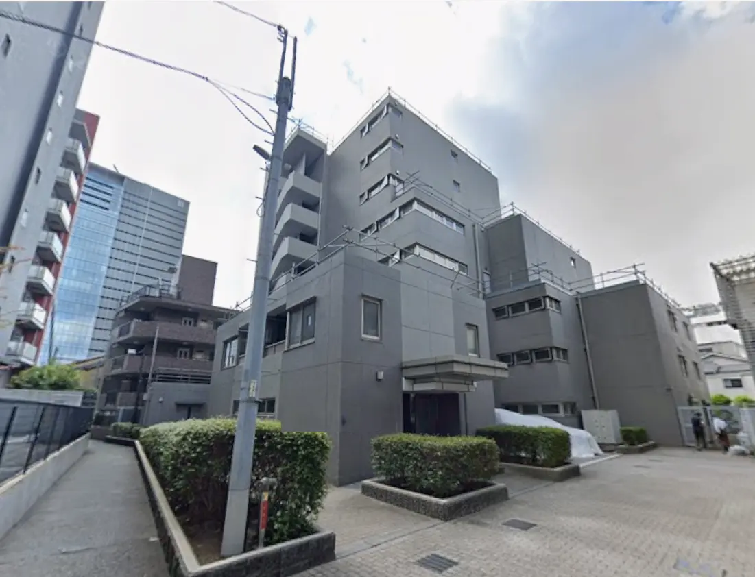 - モダンなデザインの建物、グレーの外壁と緑の植栽が整えられた歩道のある都市の風景