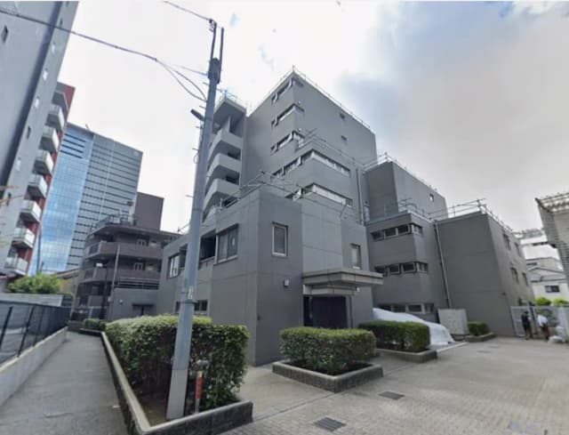 - モダンなデザインの建物、グレーの外壁と緑の植栽が整えられた歩道のある都市の風景