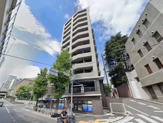 - モダンな高層マンションの外観、青空と周囲の街並みが映える都市景観