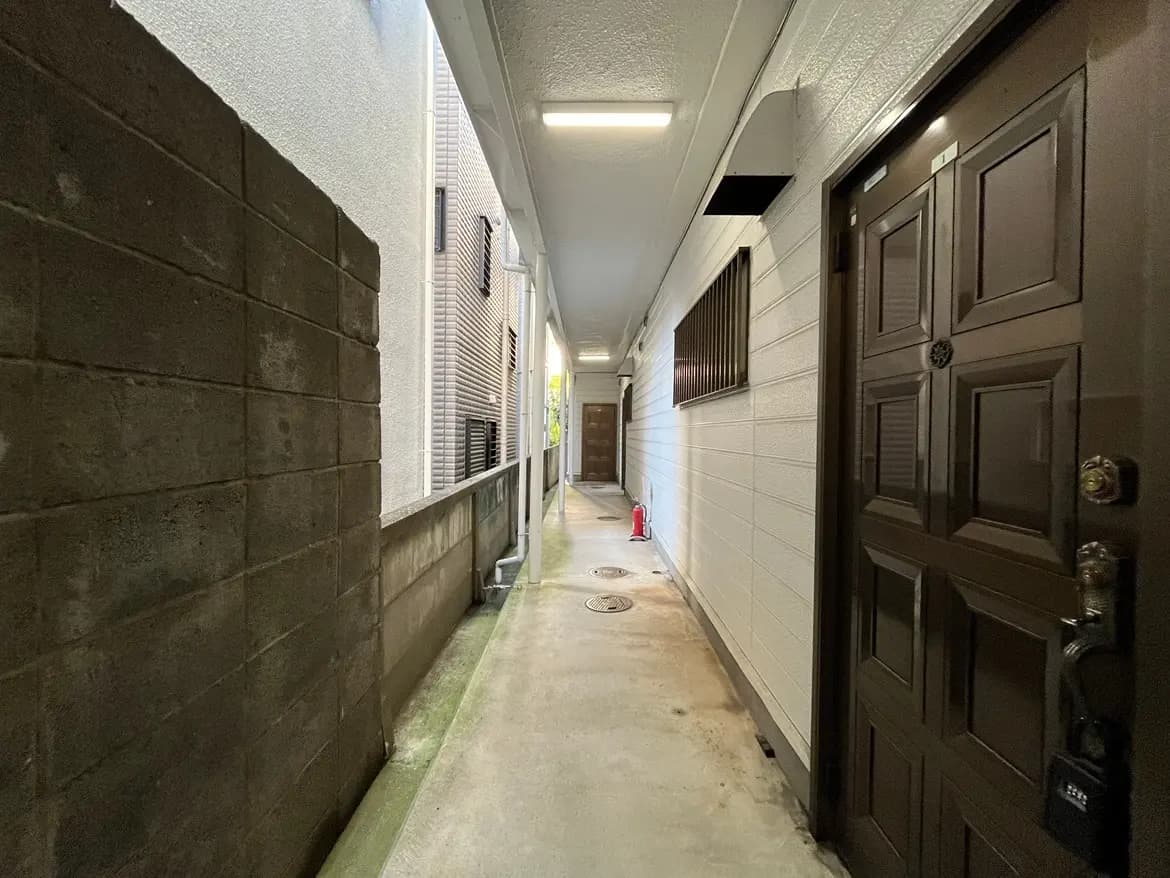 - 管理されたアパートの廊下、コンクリートの壁とドア、明るい照明と消火器が設置された安全な環境