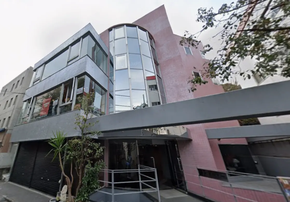 - 近代的な外観のビル、ガラス窓と赤いタイルの壁、緑の植物が施されたエントランスの景観