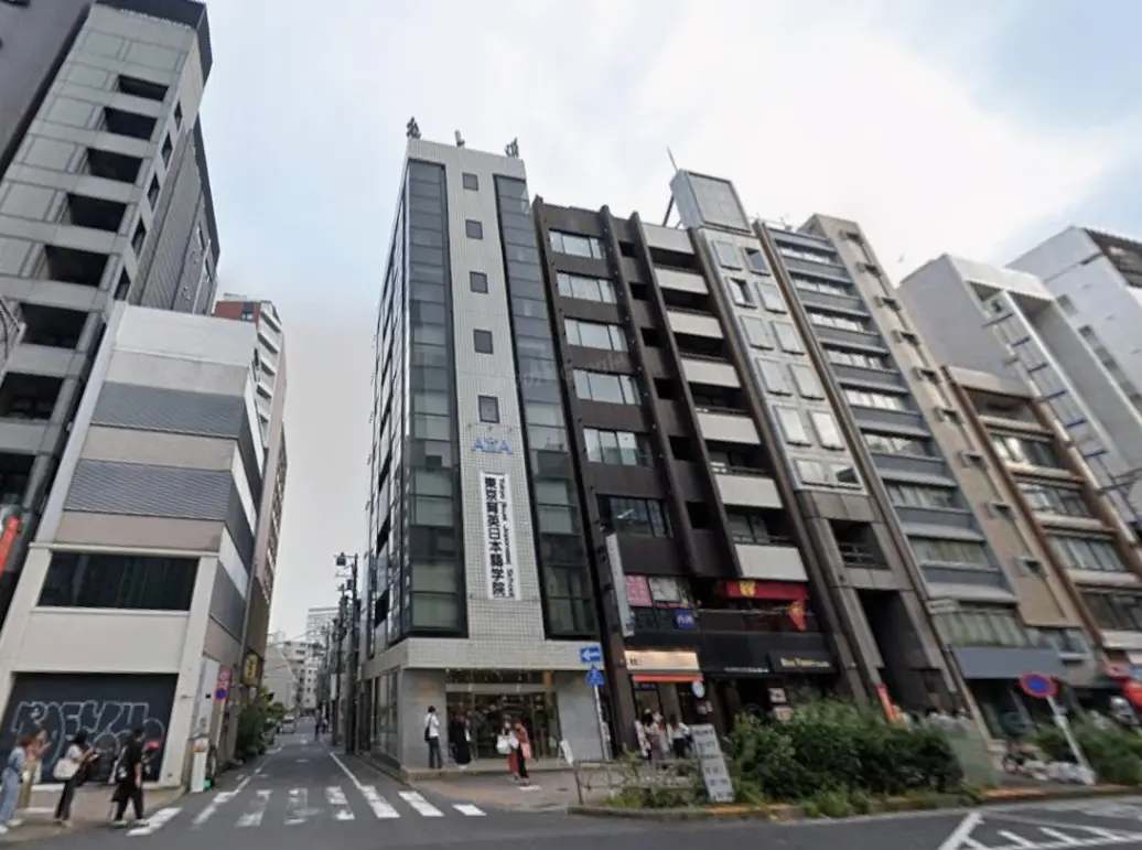 - 都市の中心部に立つ現代的なビル群、道路には歩行者や横断歩道があり、周囲に飲食店や店舗が点在する風景