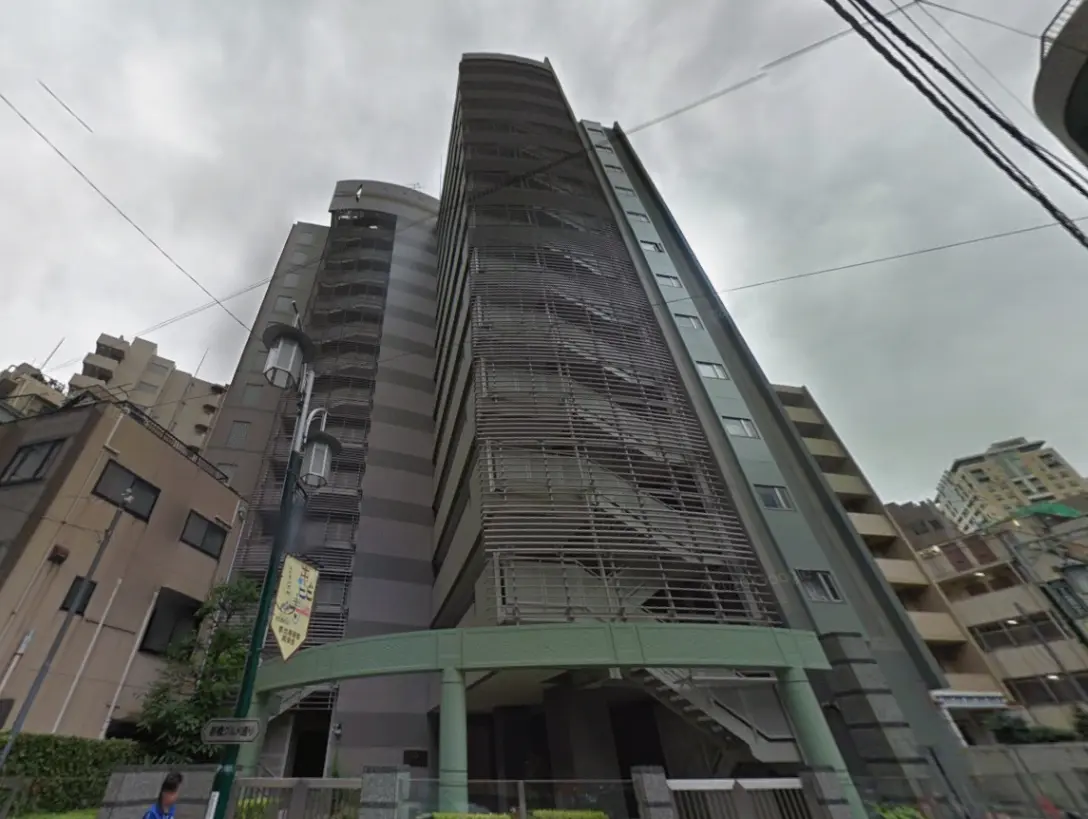 高層ビルの外観、現代的なデザインのファサードと階段、周囲の建物が写った都市の風景