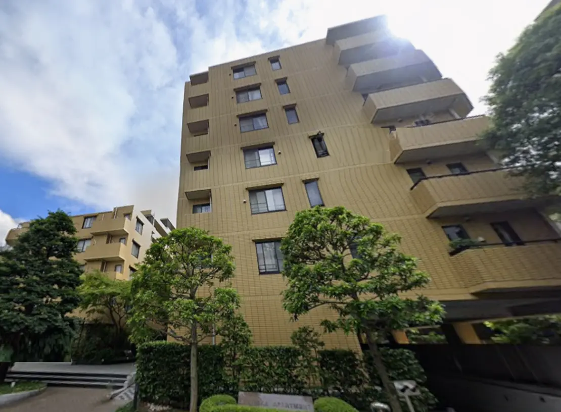 - 明るい外観のアパートメントビル、緑の植栽に囲まれたエントランスとバルコニーのあるデザイン