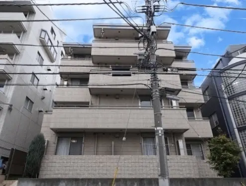 - 都市型マンションの外観、モダンなデザインで電線が張り巡らされた風景、晴れた空を背景にした建物