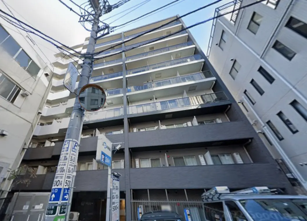 - モダンなデザインの集合住宅、バルコニー付きの外観、周囲に電柱や看板がある街並み