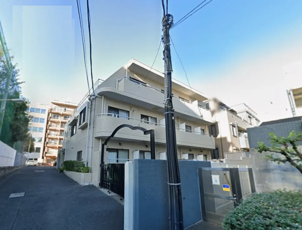 - 都心に位置するモダンなアパートメントの外観、周囲に他の建物があり、線路に沿った環境が特徴的な風景