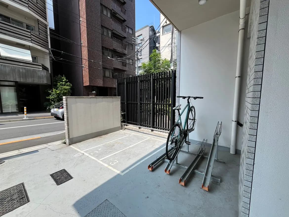 - 自転車ラックに停められた自転車、近くには都市のビルが並ぶ静かな駐車スペースの様子