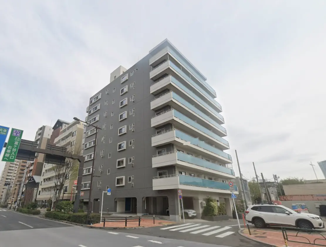 - 都市型マンションの外観、モダンなデザインのファサードとバルコニー、周囲の街並みが見える風景