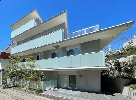 現代的なデザインの白い外壁と青いガラスバルコニーを備えた3階建ての住宅外観