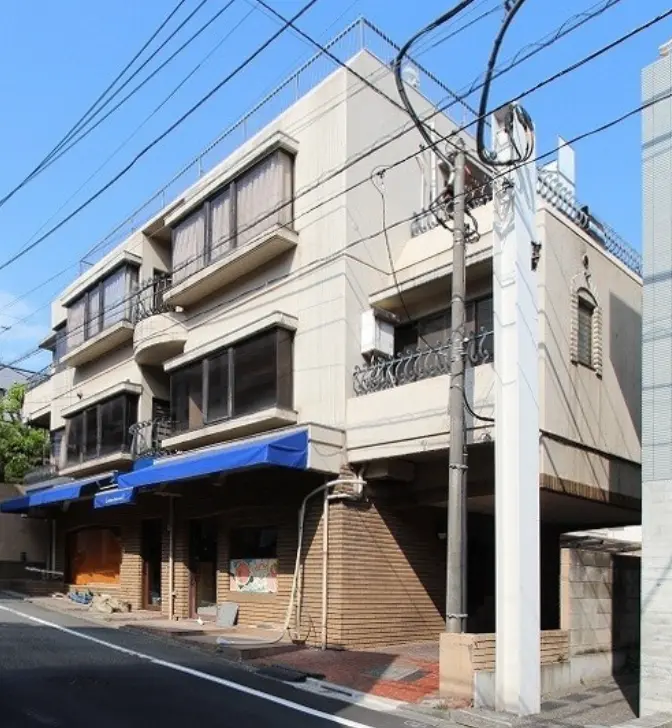 日本の住宅街にあるモダンな外観のマンションビル、店舗スペース付き、青空の下での街路景観