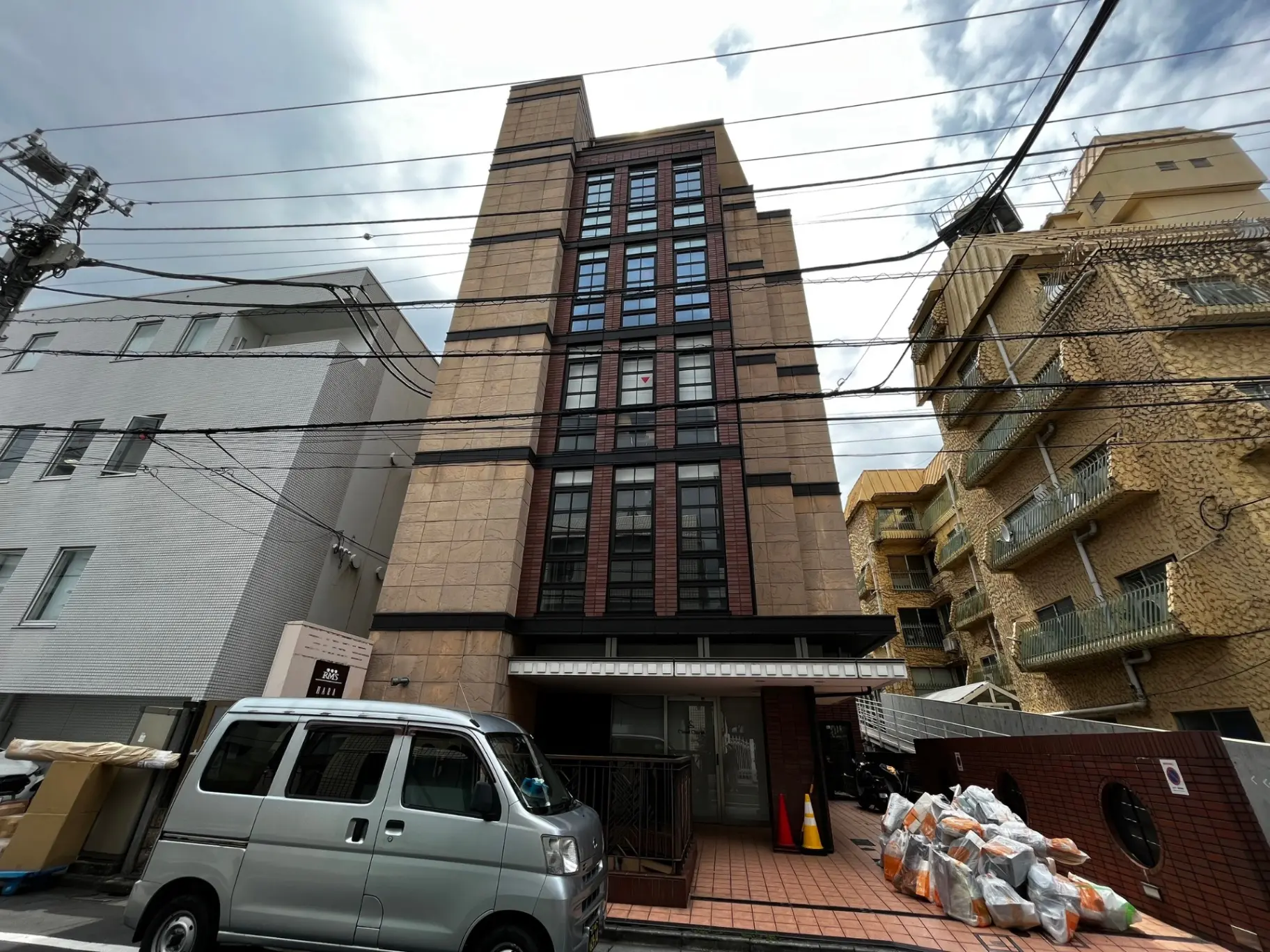 現代的な外観の都市型アパートメントビル、電線が張り巡らされた街並みの一角