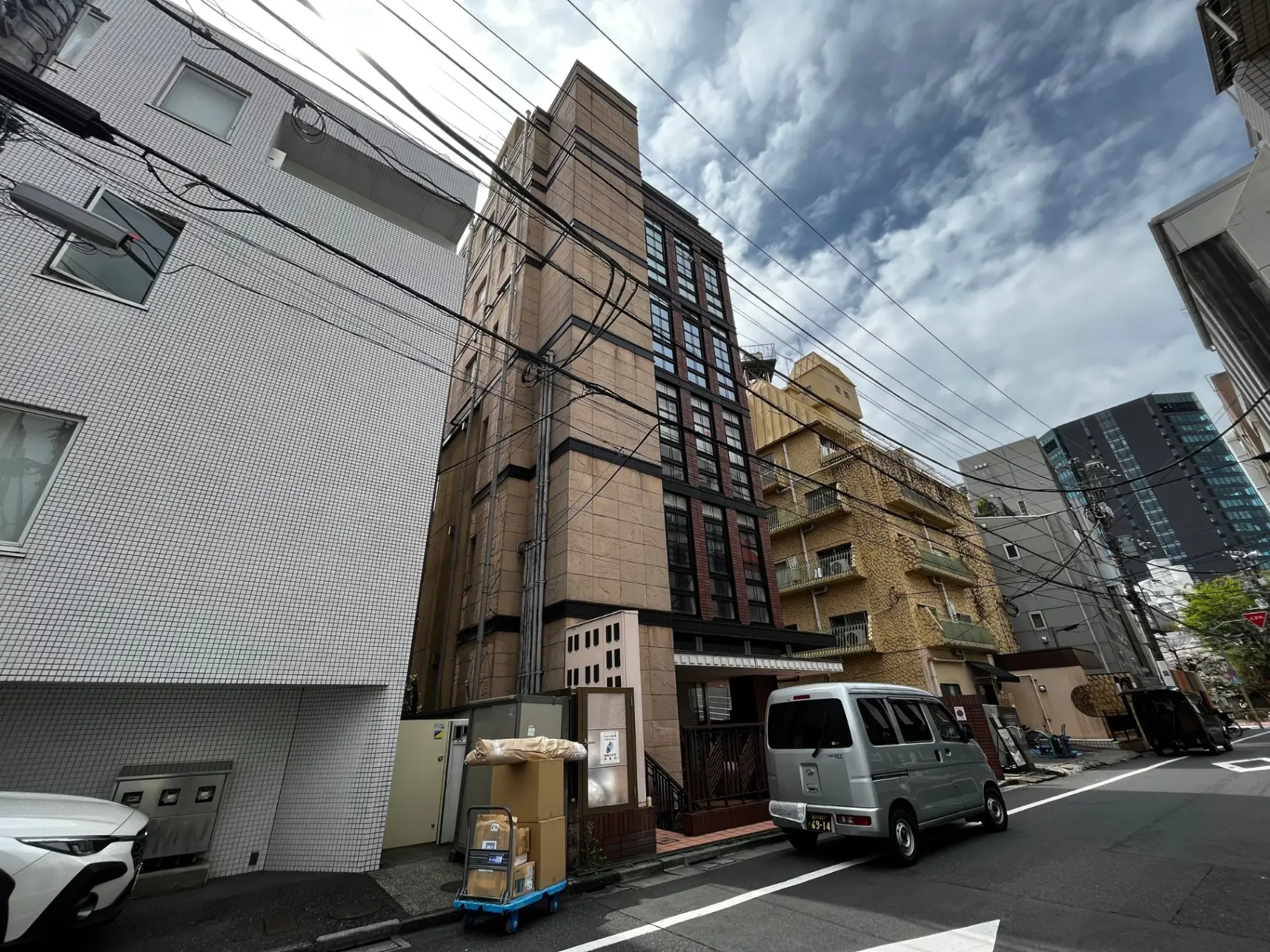 都心の繁華街の路地にあるビルとアパートメント、電線が走る都市風景