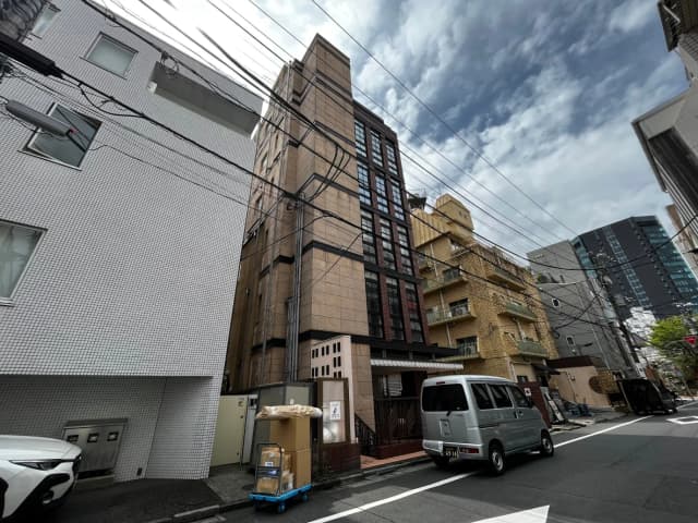 都心の繁華街の路地にあるビルとアパートメント、電線が走る都市風景