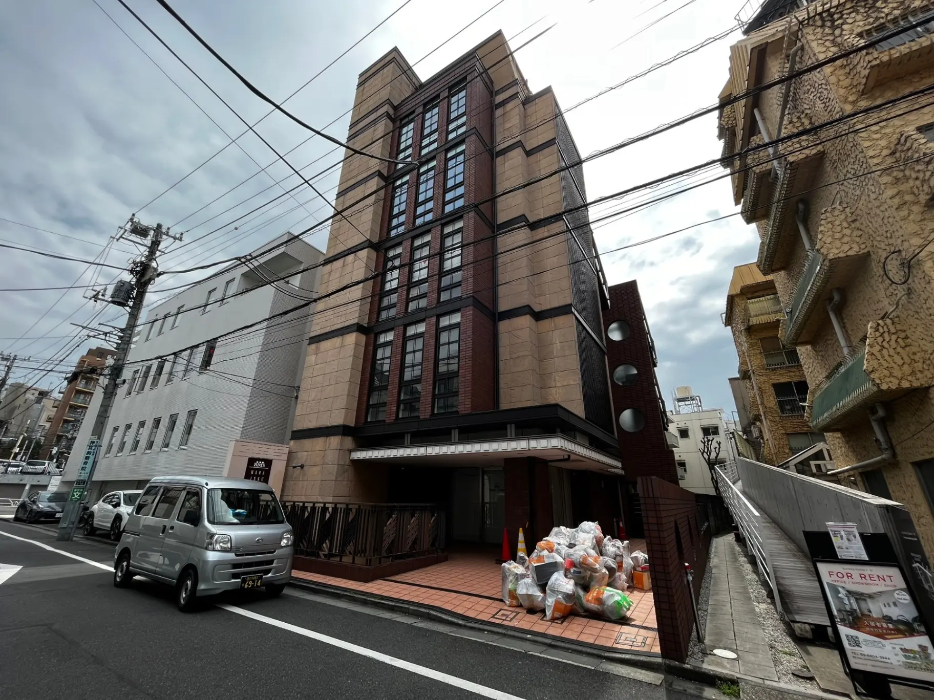 都市の中心部に位置するモダンなデザインのビル、賃貸物件あり、電柱と建物の外観