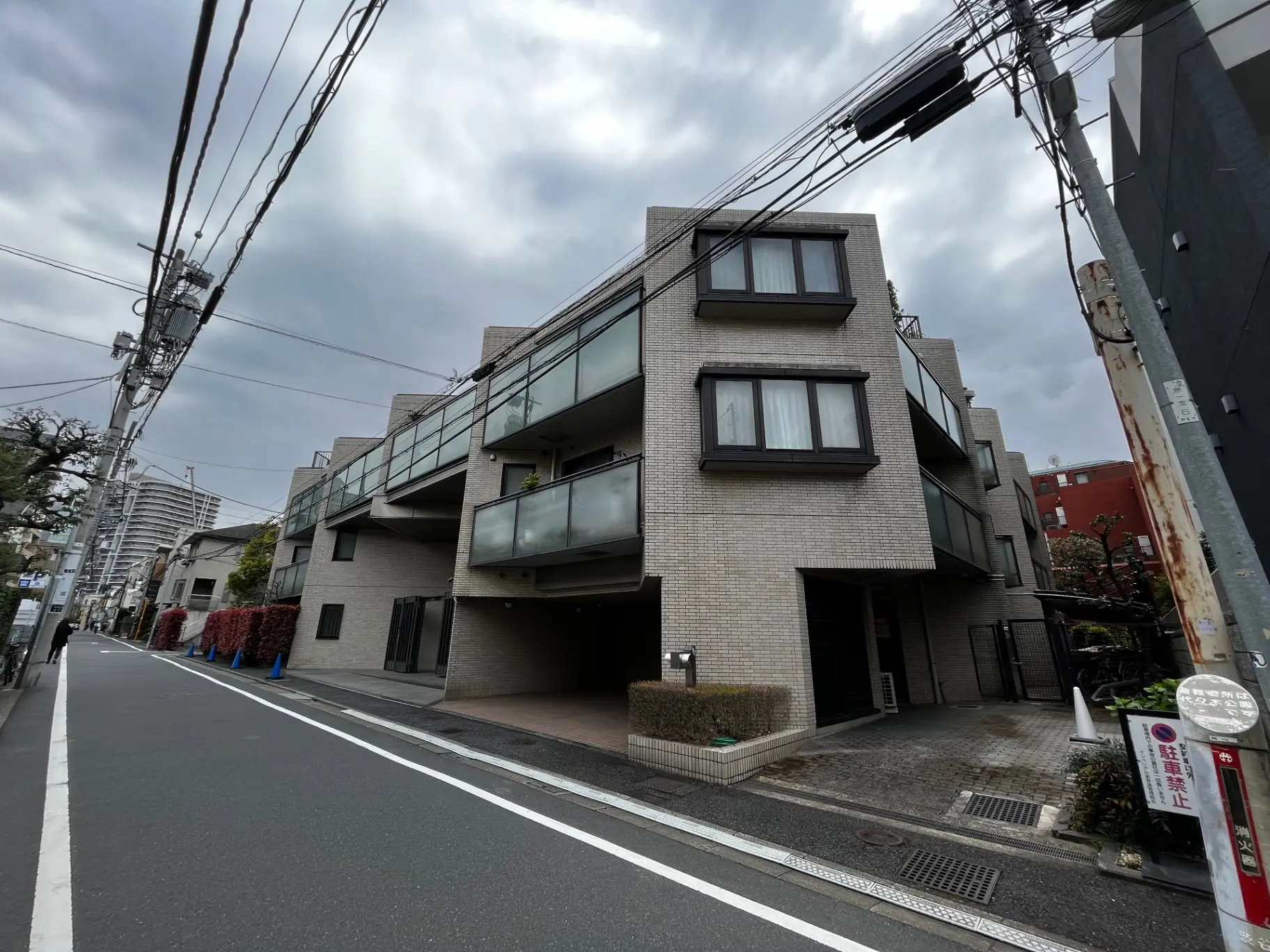 現代的な外観の都市型マンション、グレーの外壁、大きな窓、アスファルト道路沿い