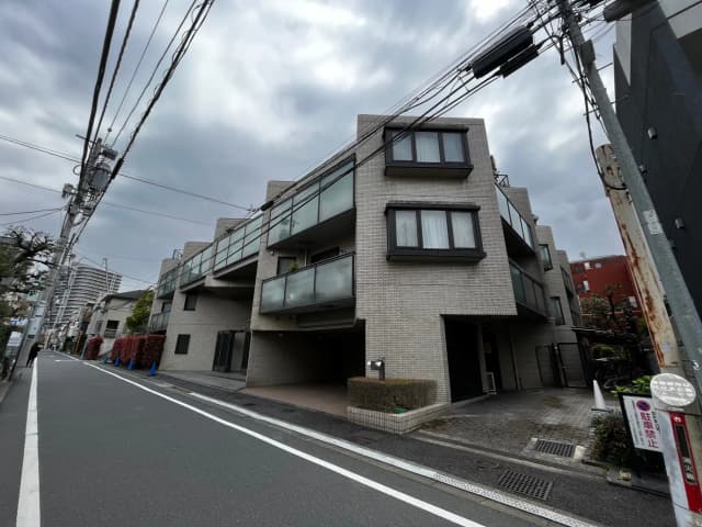 現代的な外観の都市型マンション、グレーの外壁、大きな窓、アスファルト道路沿い