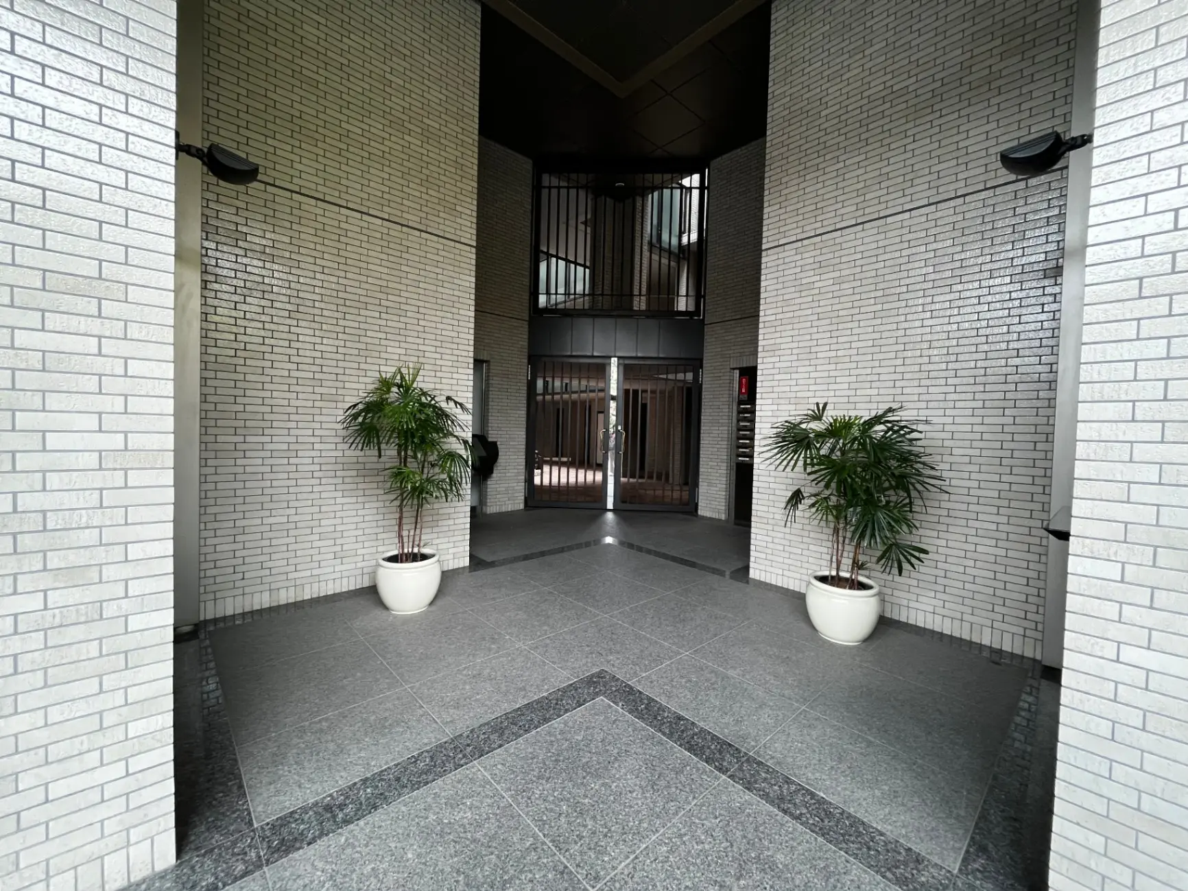 白いレンガの壁が特徴的なモダンなビルのエントランスホール、観葉植物が置かれた開放的なスペース