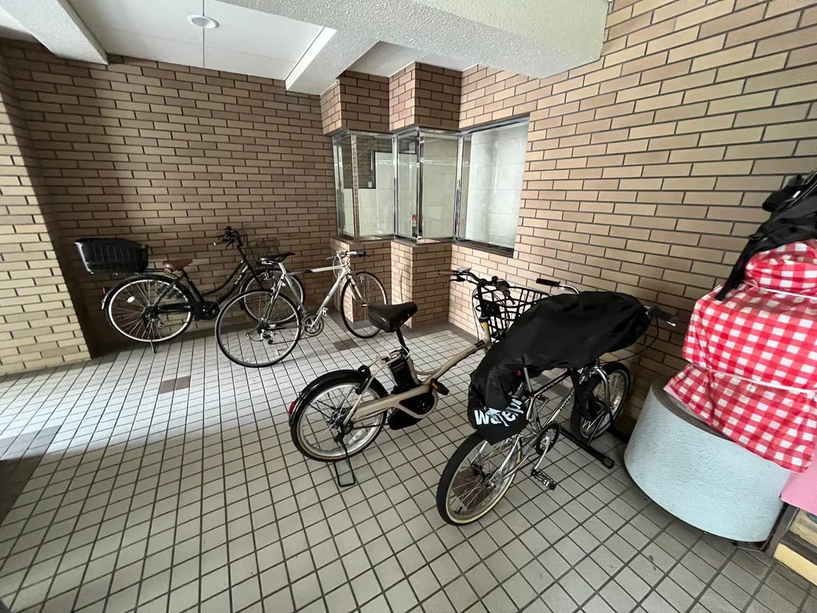 - 煉瓦造りの壁に囲まれた自転車置き場、数台の自転車と整理されたタイルの床が特徴のインテリア