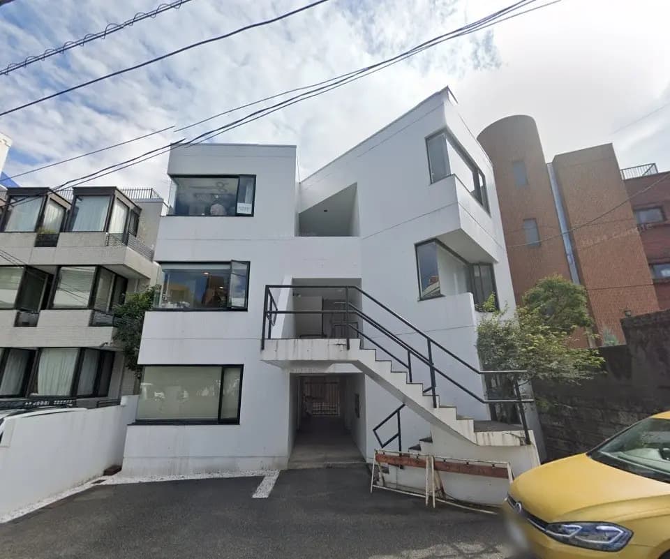 モダンな白い外観の都会的なデザインの建物、外階段付き、通りに面した住宅街の一角